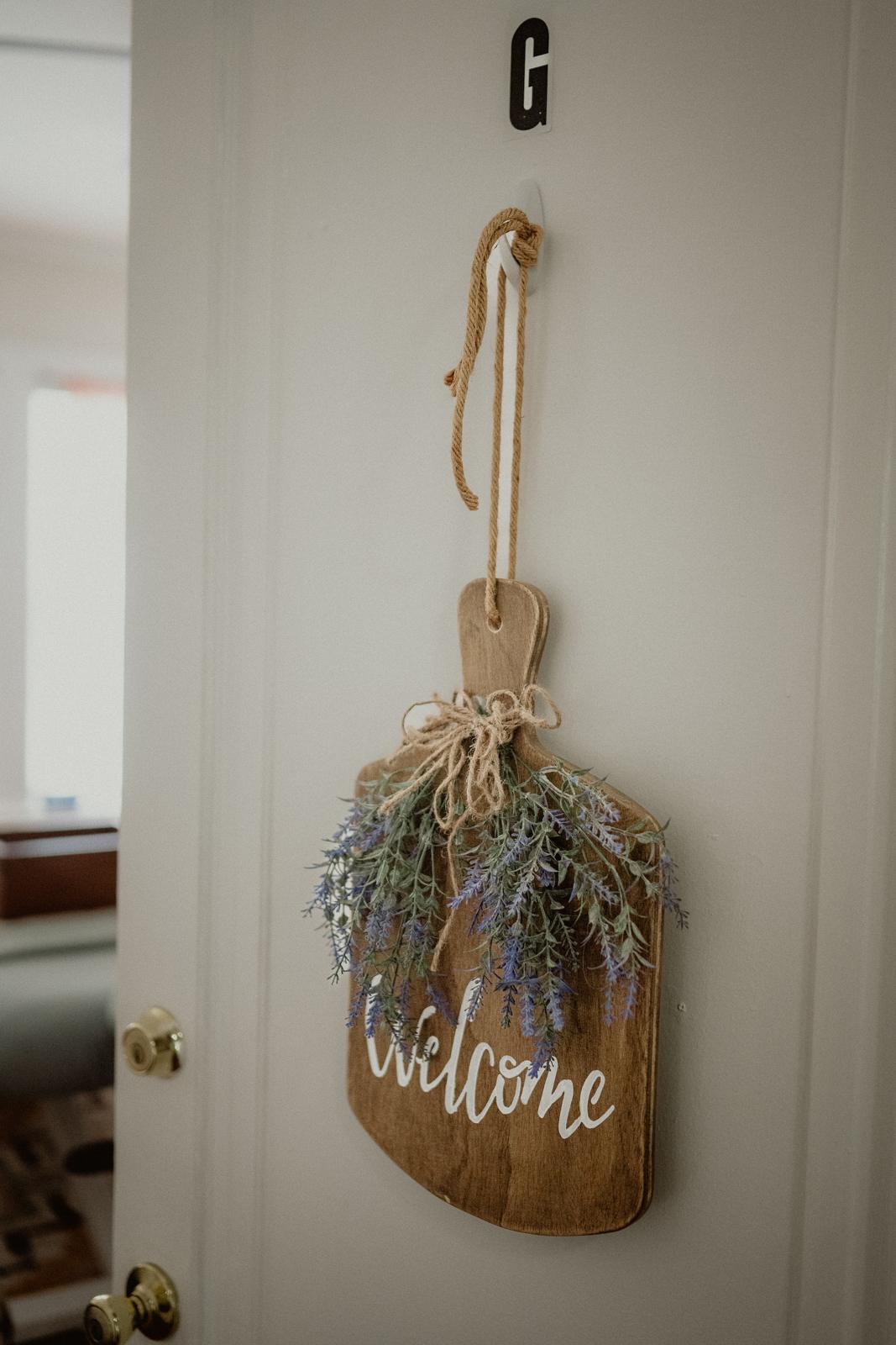 The door of Suite G with a wooden welcome sign and dried lavender